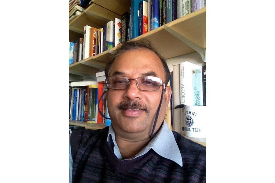 Ruppa Thulasiram wearing an eyeglass and smiling at the camera.