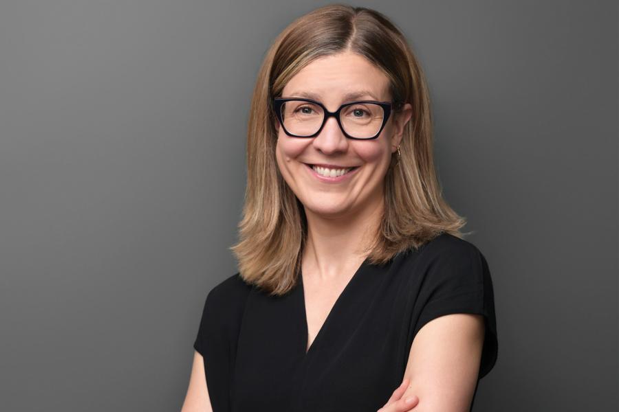 Angela Kuchison wearing a black top and an eyeglass smiling at the camera.