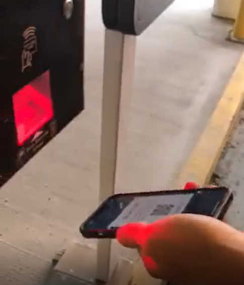 Customer holding their phone under the scanner with the TIBA mobile app open to allow gate access in and out of the parkade.