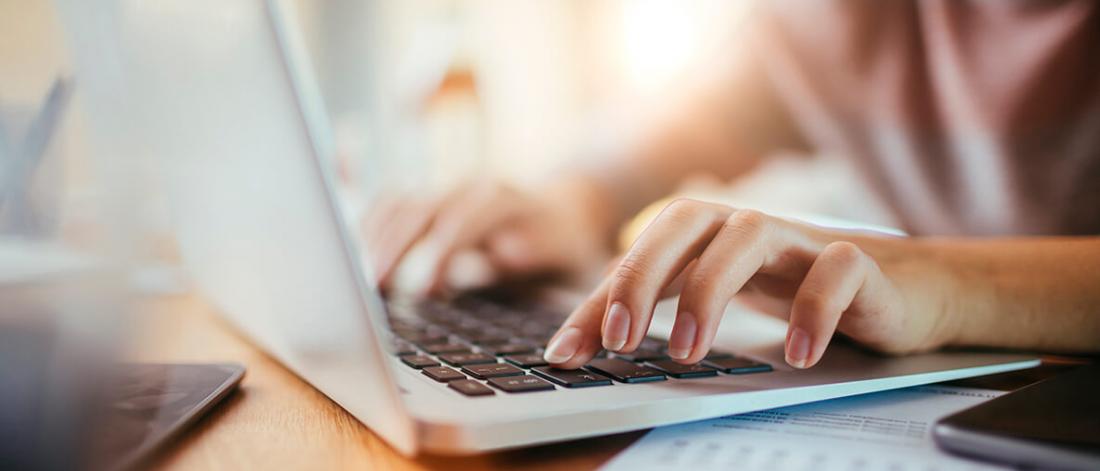 a close up of a woman's hands typing on laptop