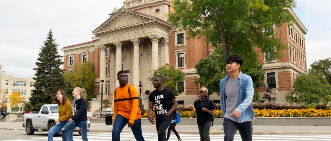 A group of University of Manitoba students walking across the street in front of the Administration building.