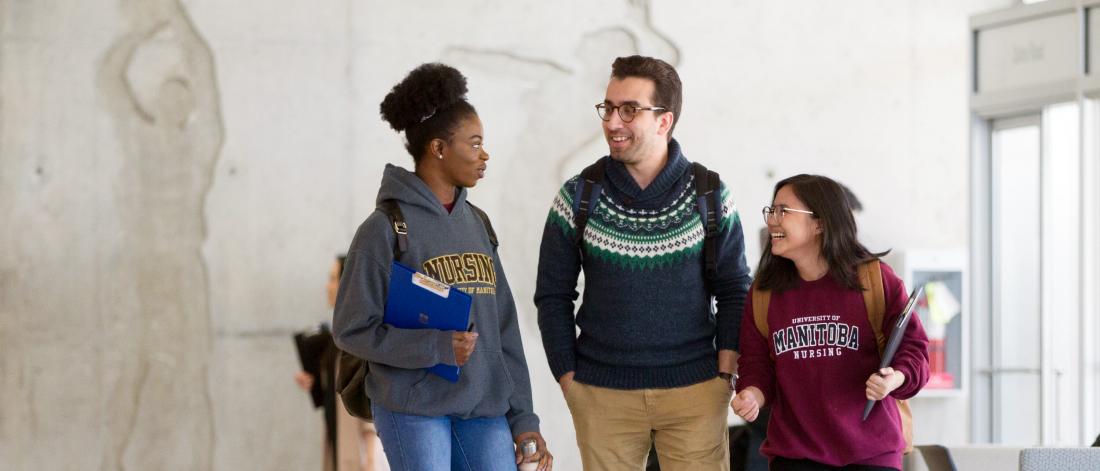 Three students walking together exchanging conversation and laughter.