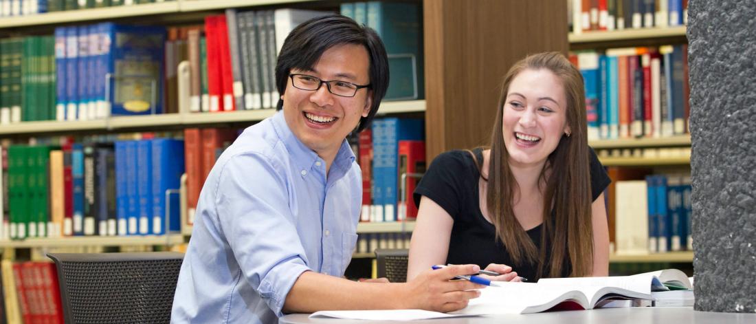 A student and tutor happily work together in a library.