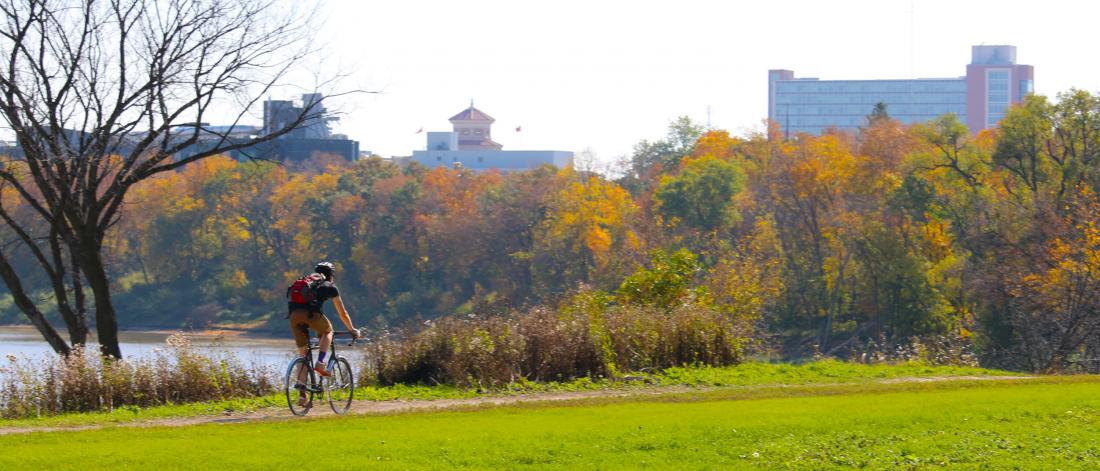 A person biking to the University of Manitoba on a scenic bike path along the Red River.