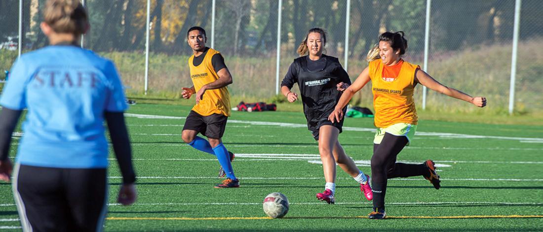 Opposing team members run for the ball during an outdoor intramural soccer game.