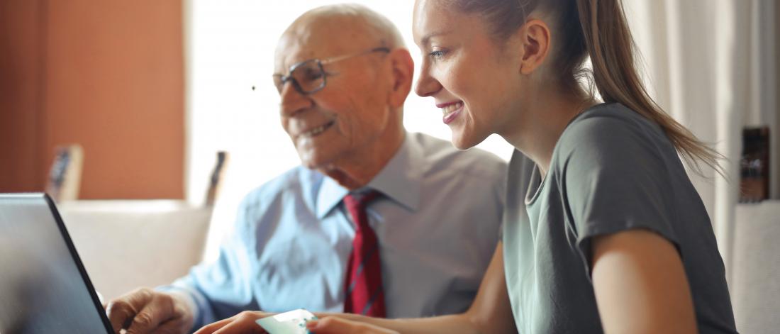 Senior man sitting next to young woman on computer