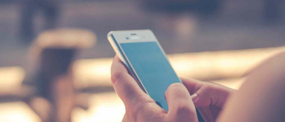 A closeup of a person's hands holding a cellular phone.