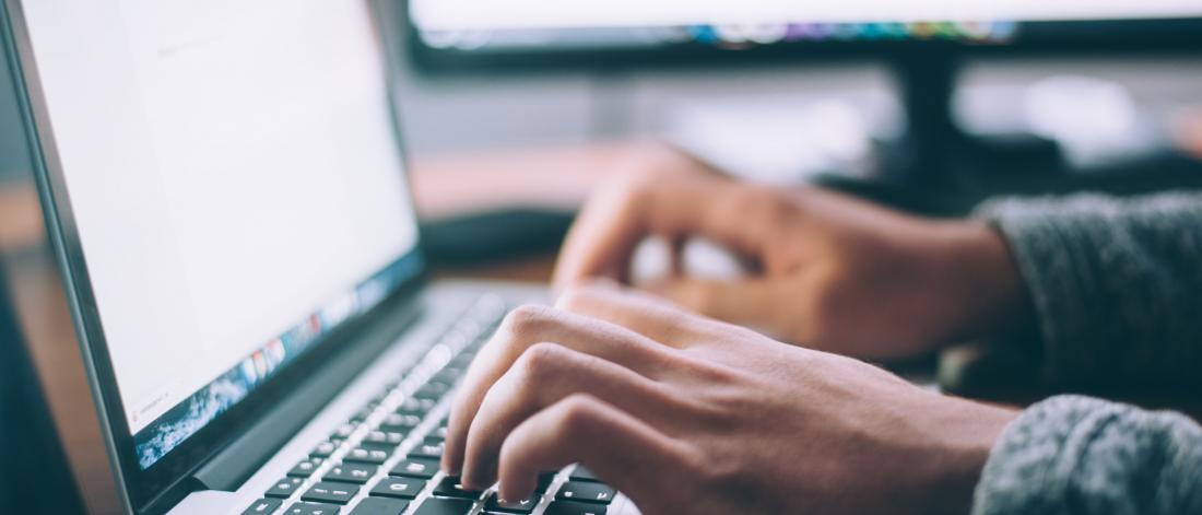 Closeup of man typing on a Macbook Pro