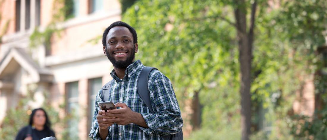 Student smiling beside his bike on campus.