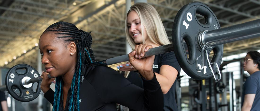 A personal trainer guides a client during a squat