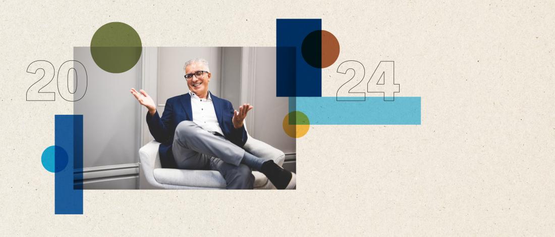  A professionally dressed man with short gray hair and glasses sits comfortably in a modern white chair, smiling and gesturing with open hands. The background features a light, textured surface with abstract geometric shapes in blue, green, and orange, and the numbers "2024" are prominently displayed in a modern, outlined font style.