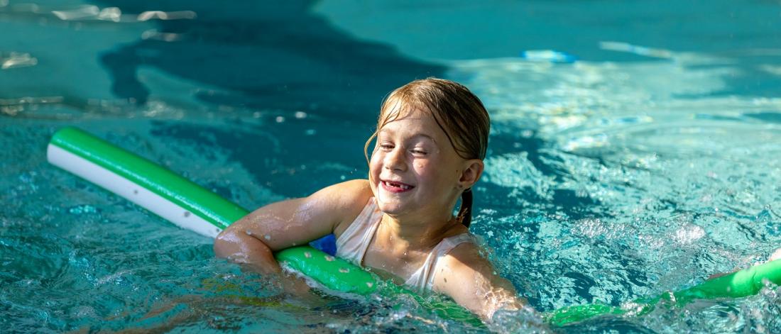 child swimming with pool noodle