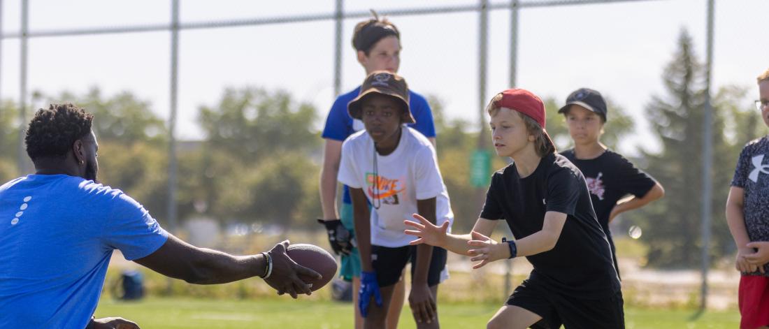 Summer camp leader and children passing a football