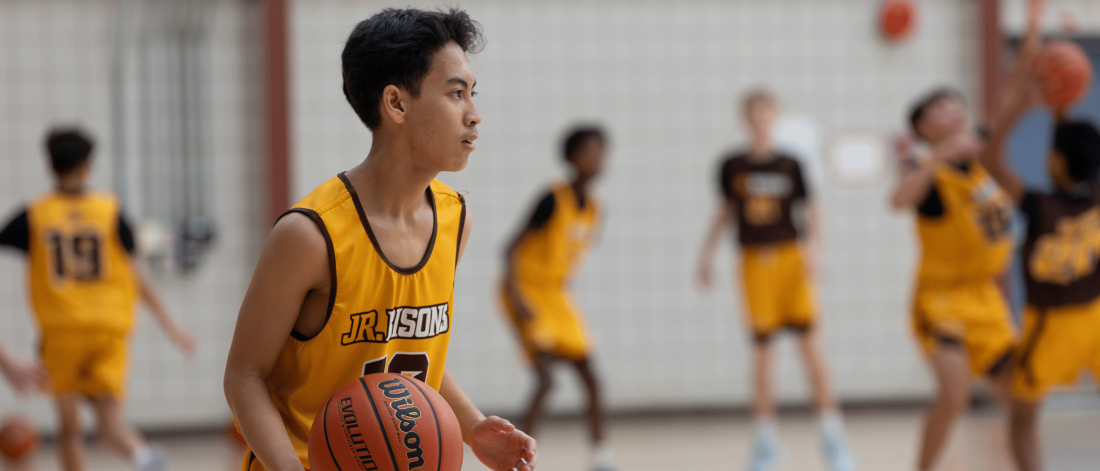 A teenage boy dribbles a basketball during a Junior Bisons practice.