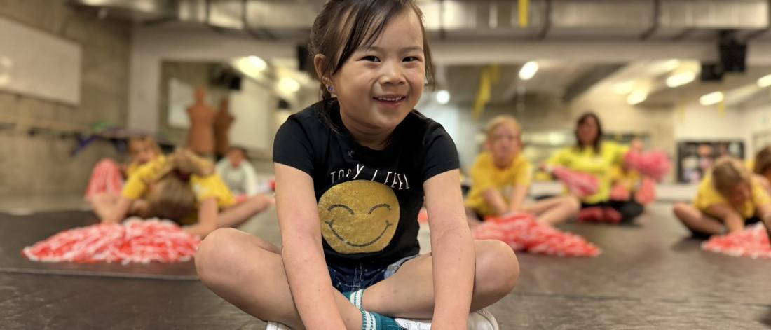 child sitting with pom poms