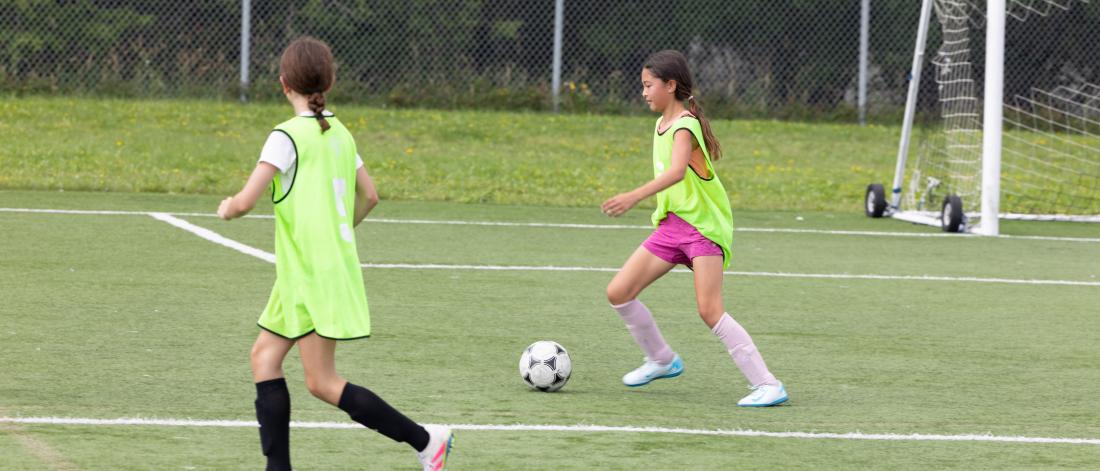A girl running with a soccer ball during a game