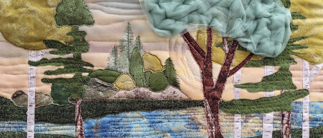 A fabric, quilted image of a forest scene with a river running through it.