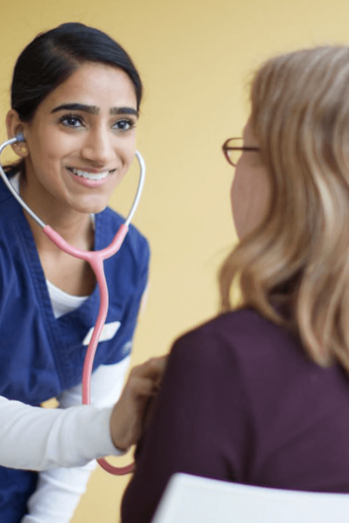 A nurse uses a stethoscope to listen to a patients heartbeat.