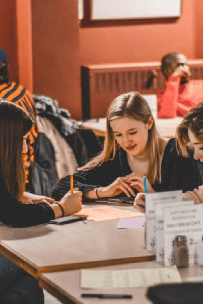 A small group of students seated at a table study together. 