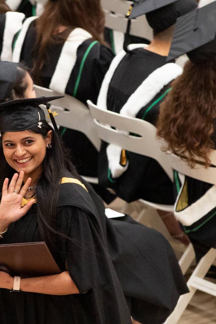 A student waves to supporters during a convocation ceremony.