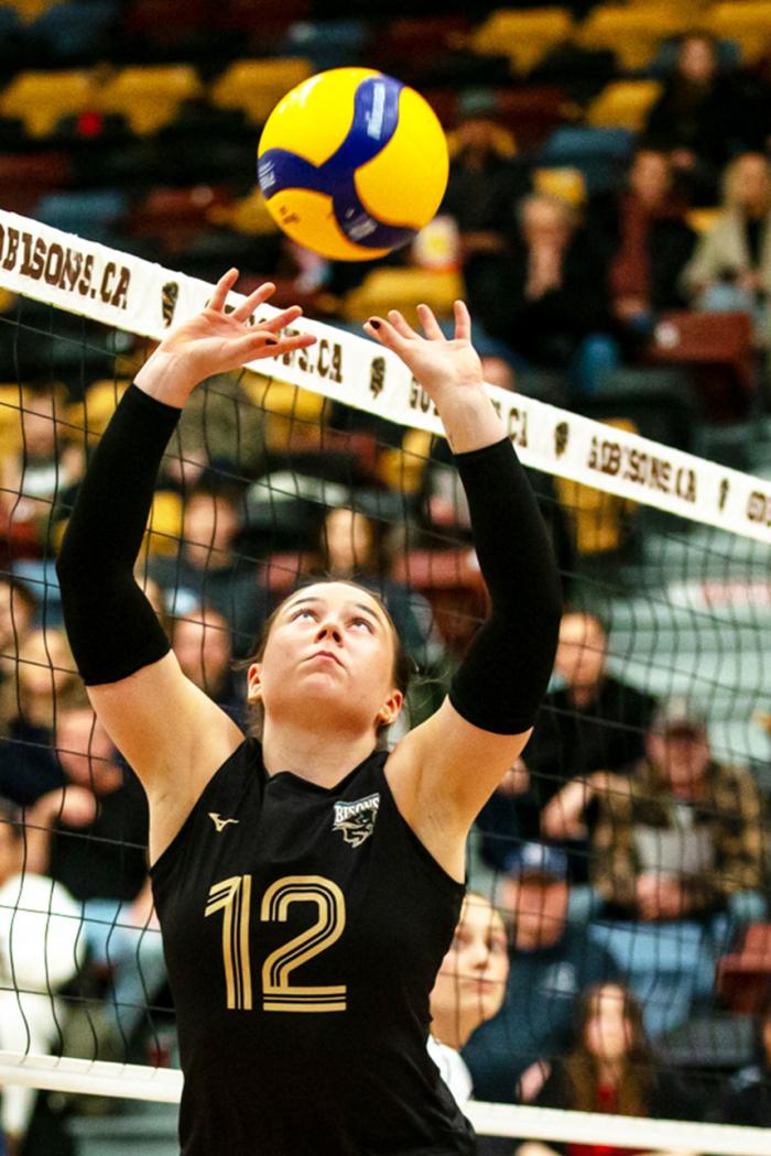 a women's volleyball team player sets the ball in action.