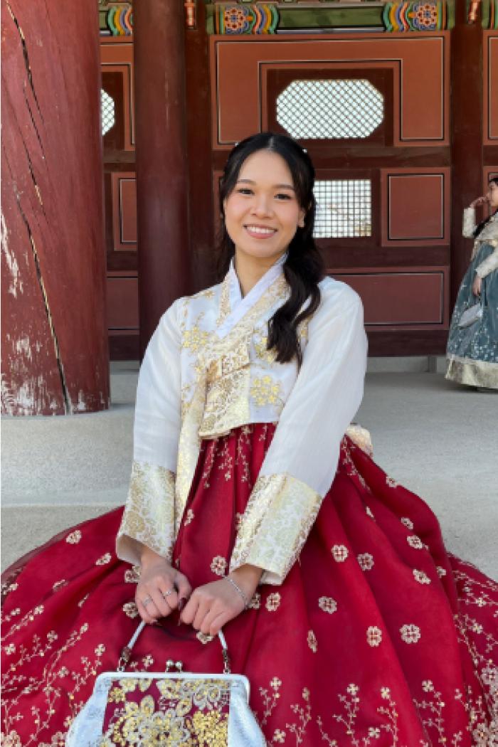 Cedey smiling at the camera dressed in a vibrant traditional-style dress.