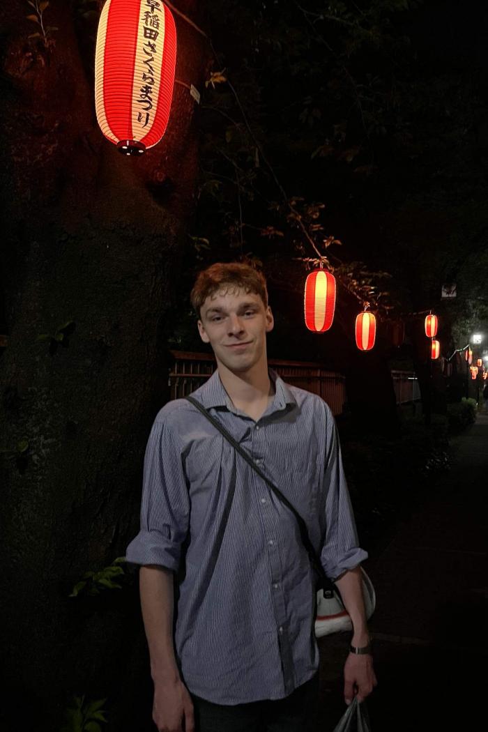 Karl poses on a street in Japan at night, with red lanterns illuminating the scene.