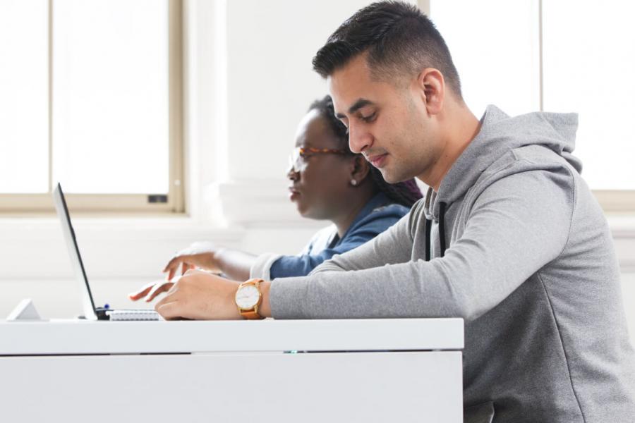 A University of Manitoba student at a desk working on a laptop.