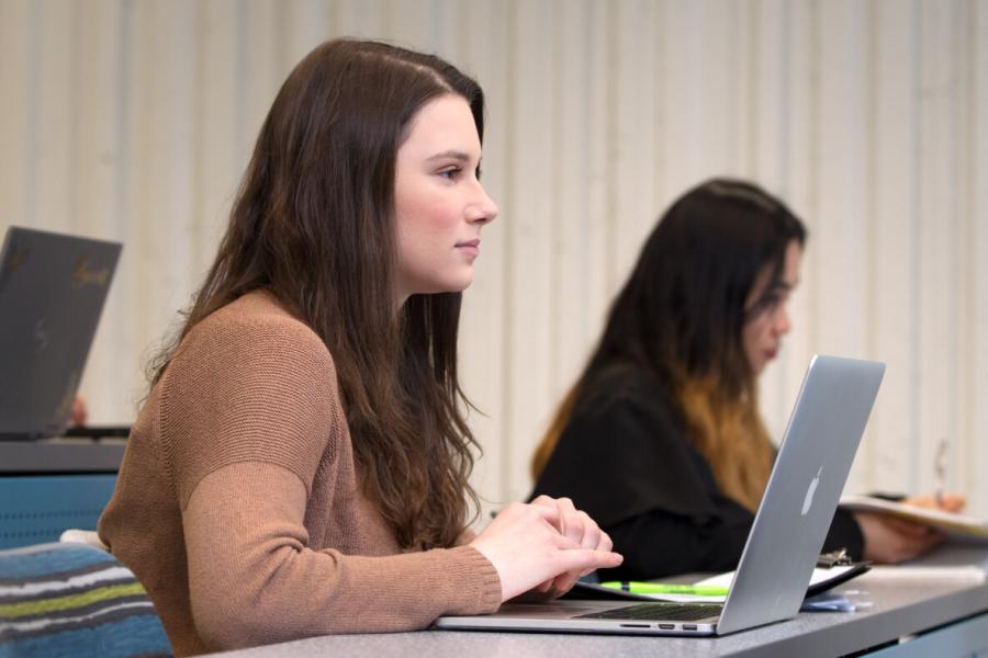 A University of Manitoba student at a desk working on a laptop.