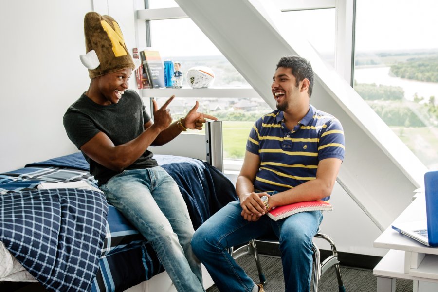 Two University of Manitoba students laughing together in a Pembina Hall Residence room.