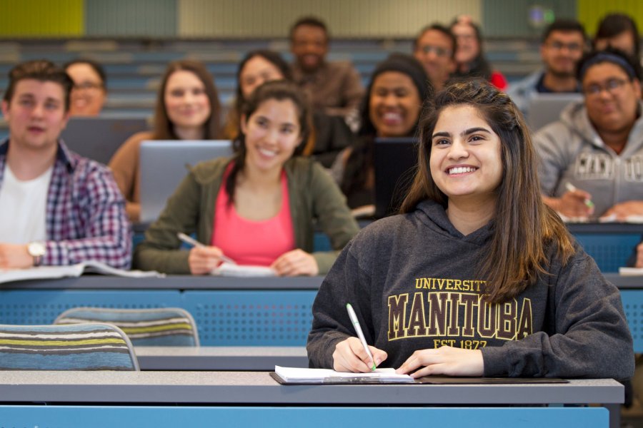 A classroom full of smiling attentive students taking notes.