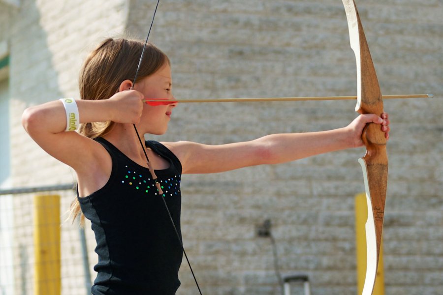 A Mini U junior raising her bow and aiming towards her target.