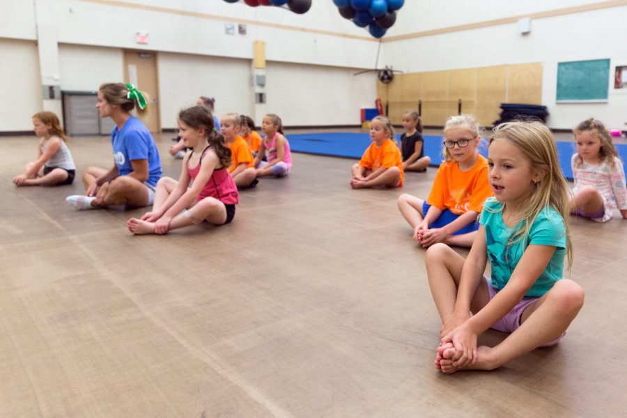 A gymnasium full of mini-u kids stretching during the cheerleading program.