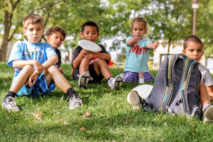 A group of children sitting outside in the grass together.