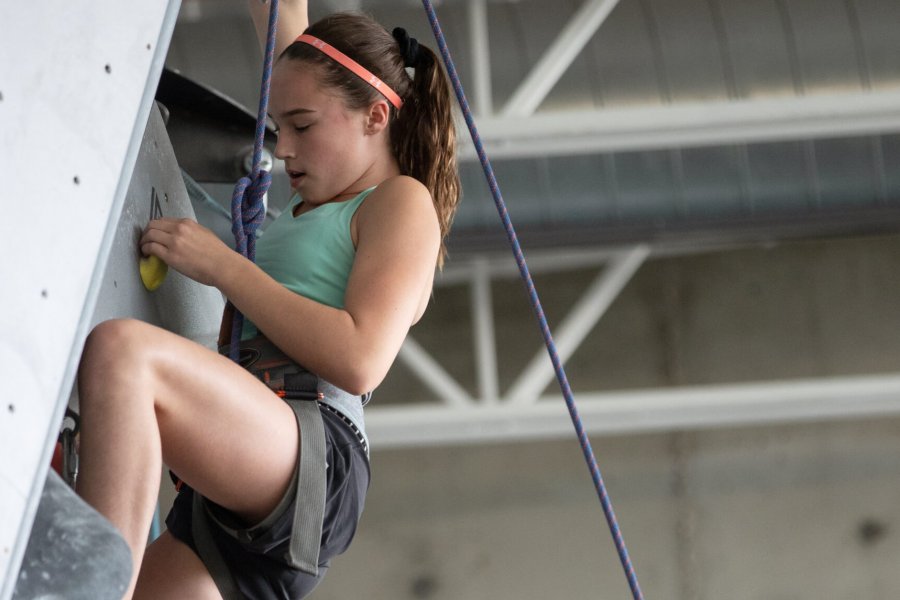 A girl climbing the climbing wall in the advanced climbing skills class.