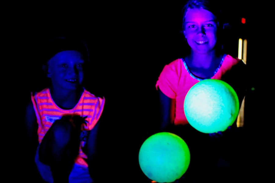 Two kids with glowing neon clothing under the black lights.