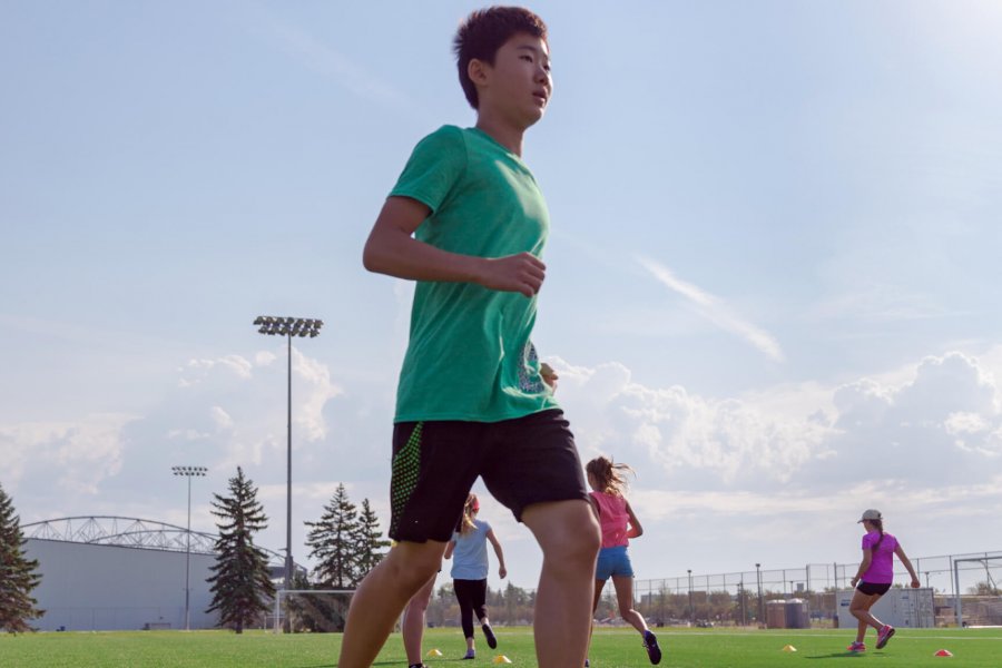 Kids running outdoors practicing soccer skills.