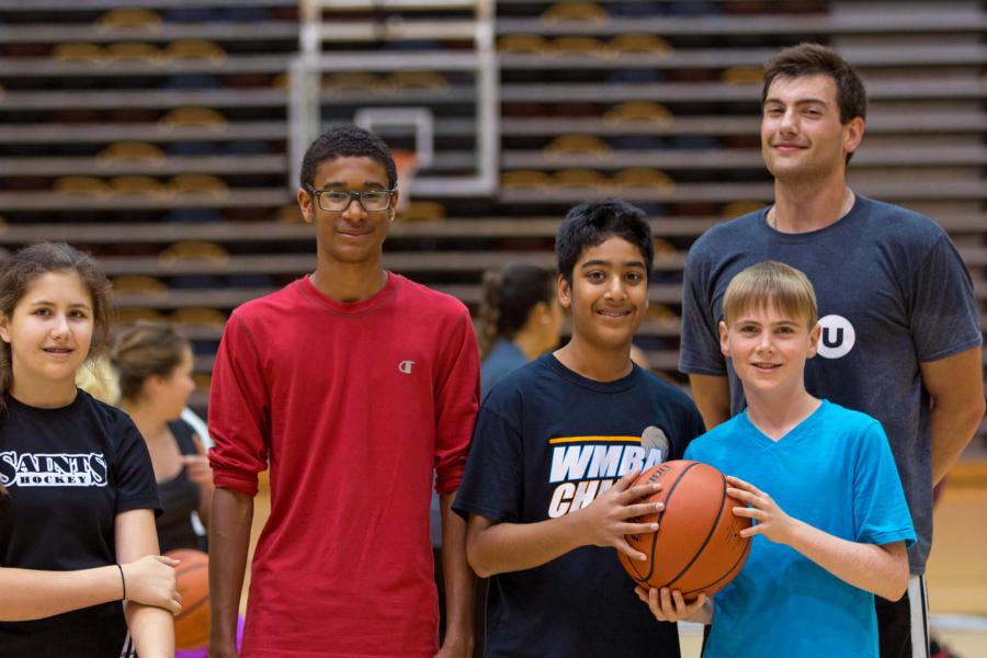 A group of young basketballers poses in the gym with their Mini U leader. 