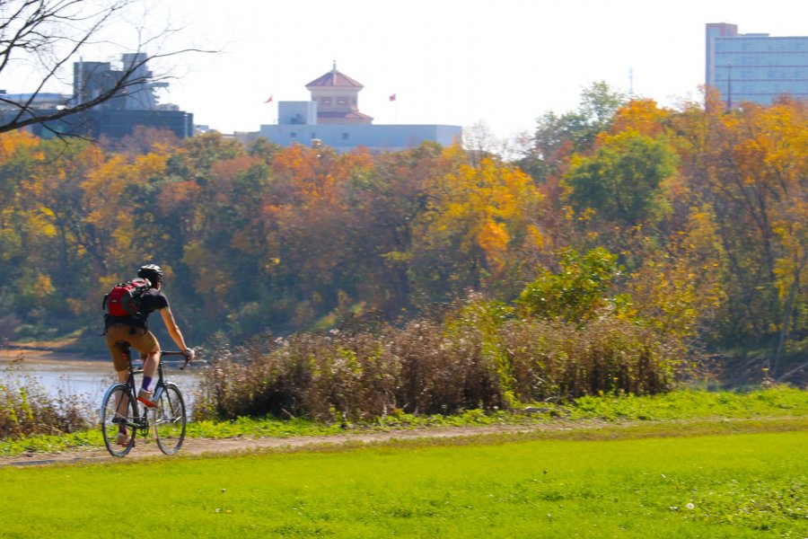 A University of Manitoba student biking to campus on a scenic bike path along the Red River.