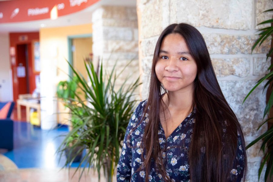 Past BMO Financial Group Indigenous Leader of Tomorrow Scholarship recipient Zoe Quill standing in the Migizii Agamik - Bald Eagle Lodge.