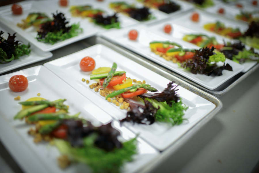 Row of plated salads including lettuce, asparagus, tomatoes and nuts