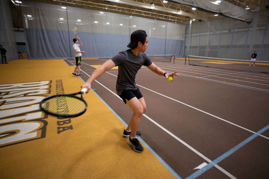 A man prepares to serve a tennis ball across the court.