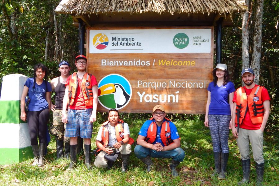 Students gather in front of a sign while on a tour in the Amazon rainforest.