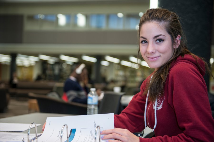 student in the library facing the camera