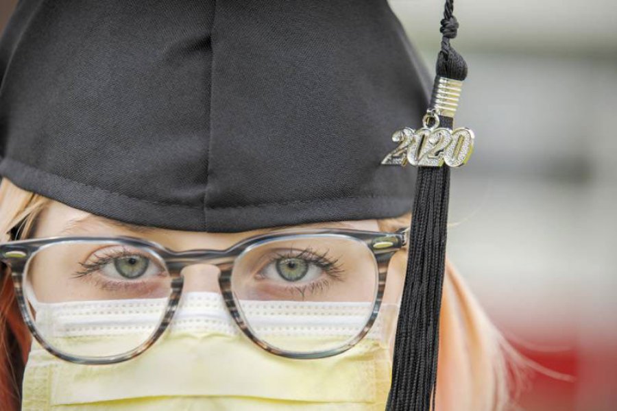 A girl wears her cap and tassel over a medical mask.