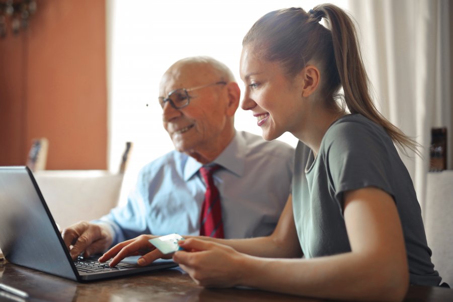 Senior man sitting next to young woman on computer