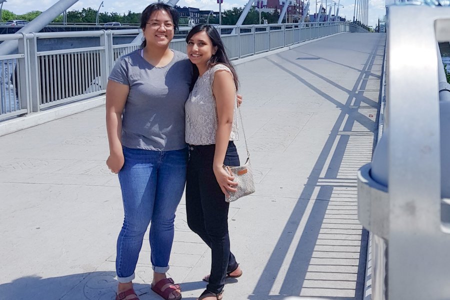 Peer Mentor, Muntaha, stands with her pair, Angelica, on the Esplanade Riel Bridge at the Forks in Winnipeg.