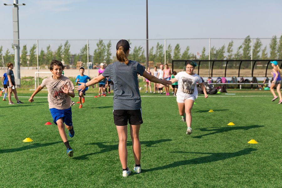 children and coach pictured outdoors on soccer field