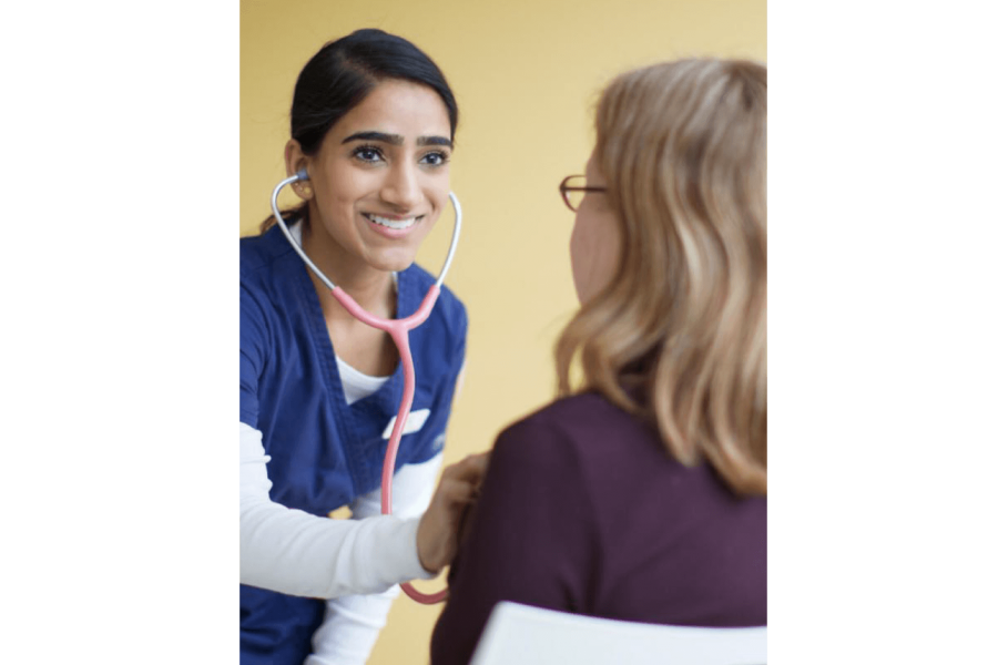 A nurse uses a stethoscope to listen to a patients heartbeat.