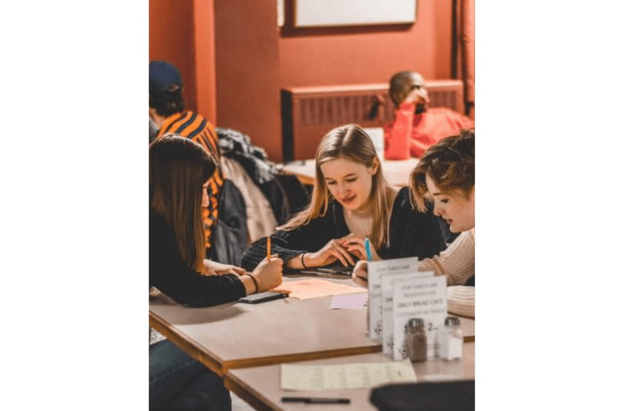 A small group of students seated at a table study together. 